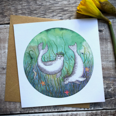 A pair of harbour seal beneath the sea with seagrass